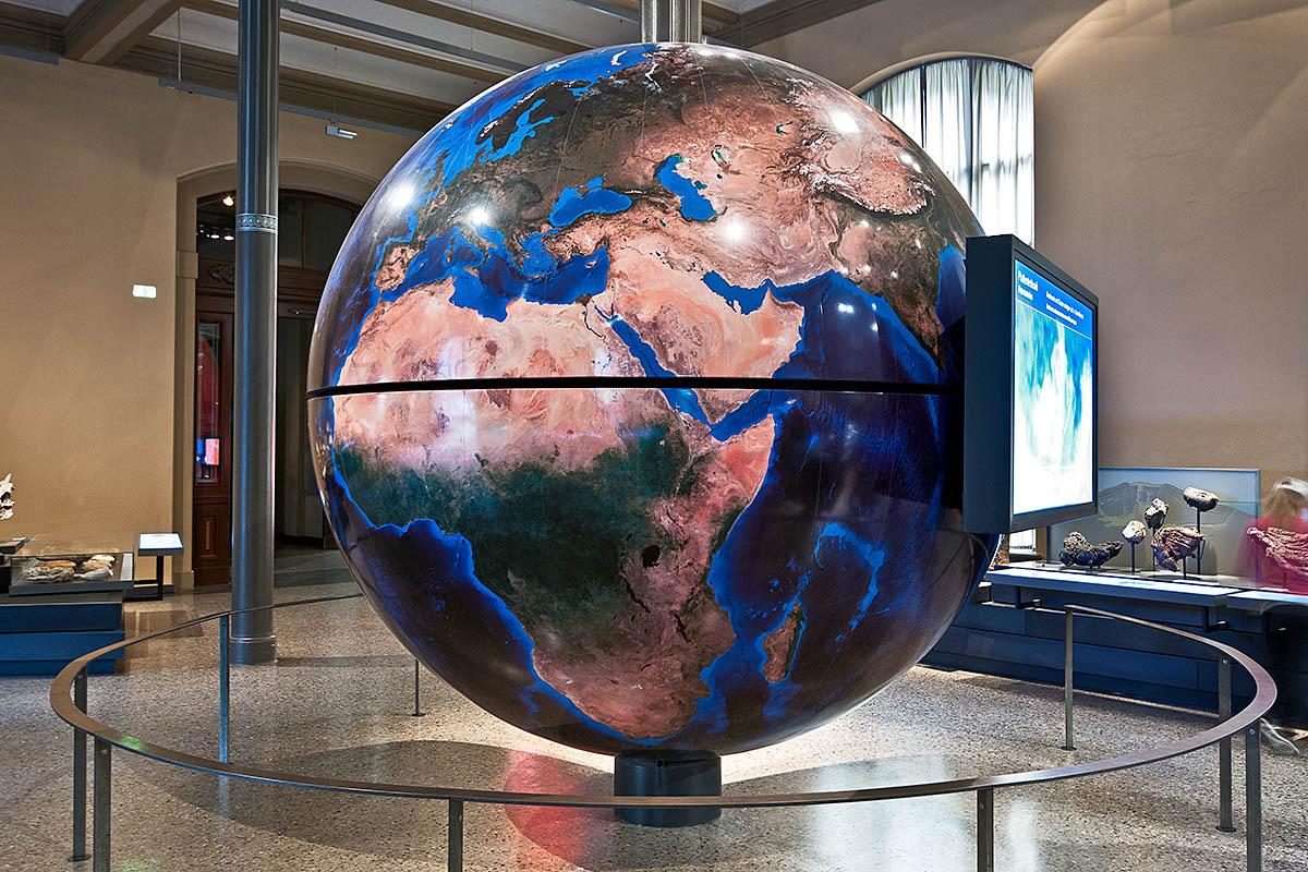Das Foto zeigt den drei Meter hohen Globus, an welchem ein Bildschirm angebracht ist, der Animationen und Filmsequenzen zu den Themen der Ausstellung zeigt.