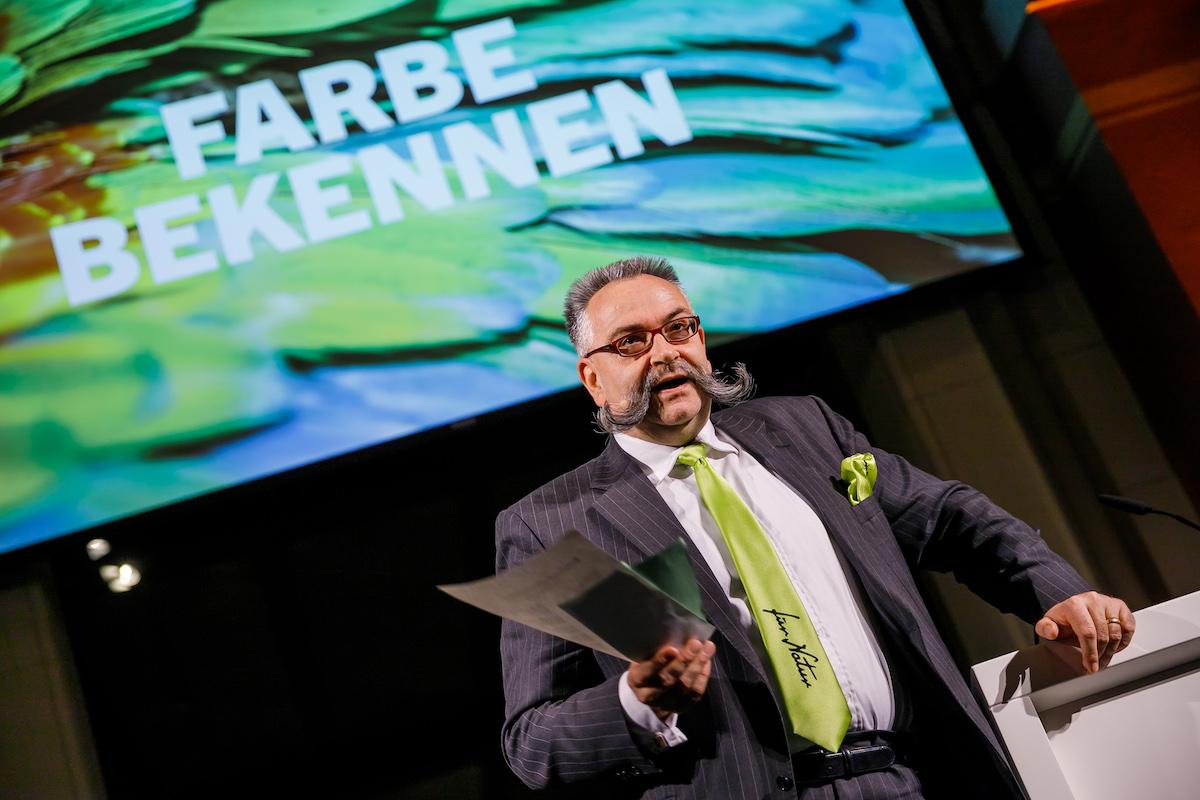 Johannes Vogel, Generaldirektor des Museums für Naturkunde Berlin, am Rednerpult im Sauriersaal. Dahinter eine Beamerfläche mit den Worten "Farbe bekennen"