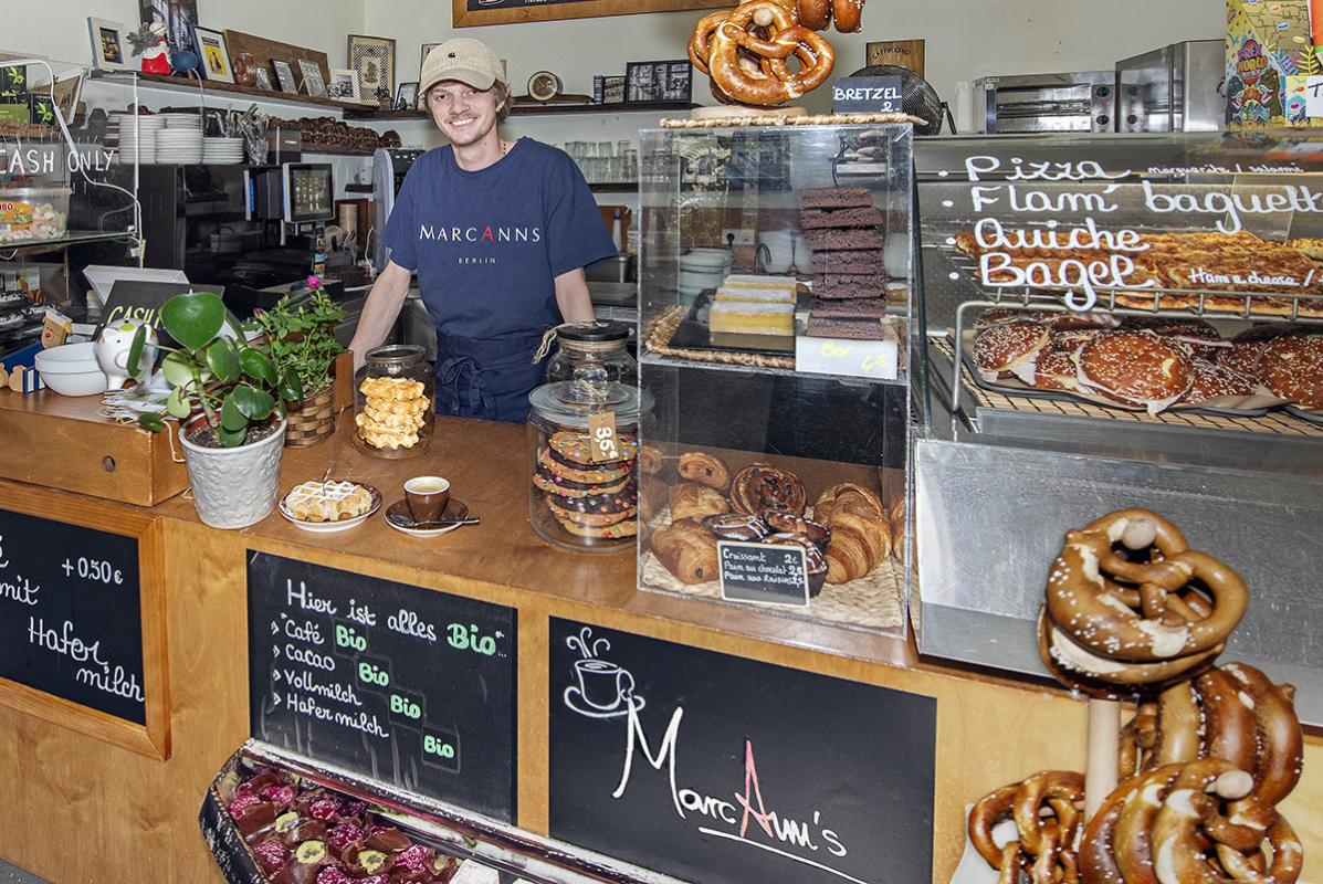 Ein Mitarbeiter des Museumscafés heißt Besuchende an der Theke willkommen