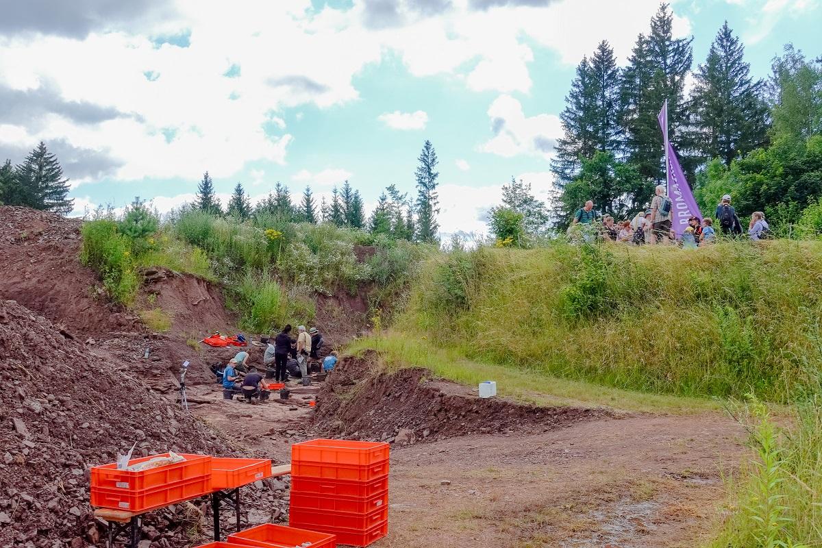 The Bromacker excavation site: On the left, the excavation team at work; on the right, visitors observing the dig from an elevated platform.