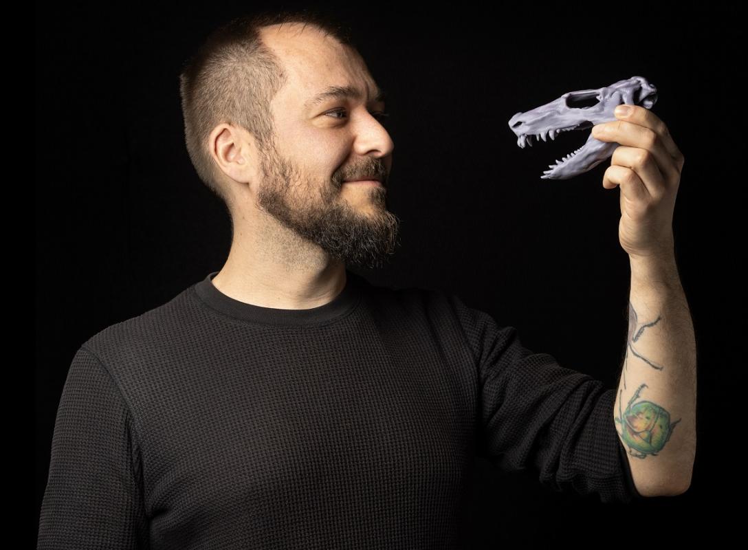 Steffen Bock holding a small 3D-printed plastic skull of an early tetrapod in his hand.