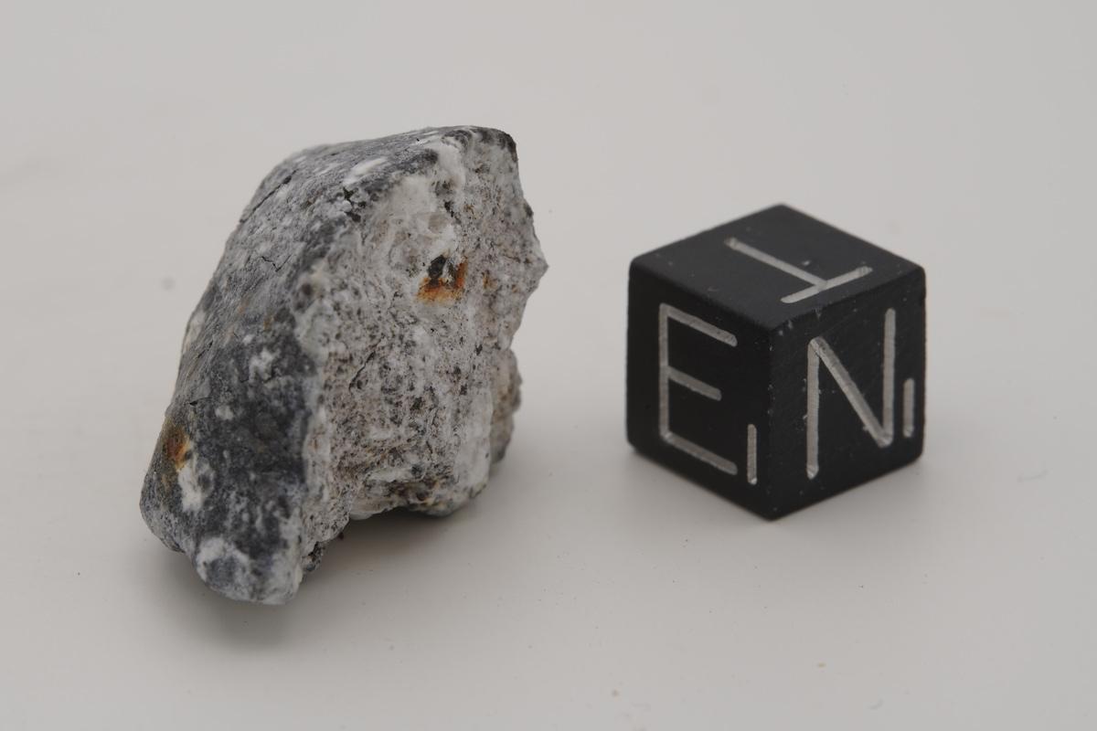 Bruchstück des Meteoriten im Größenvergleich mit einem Würfel