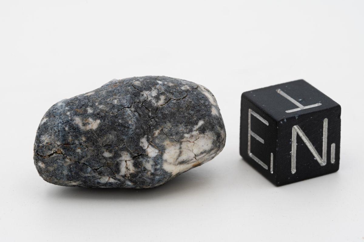 Meteorite called Ribeck in relation to a cube on a white background 
