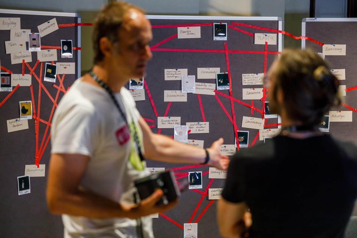 people stand in front of the figurative network of Anthropocene objects