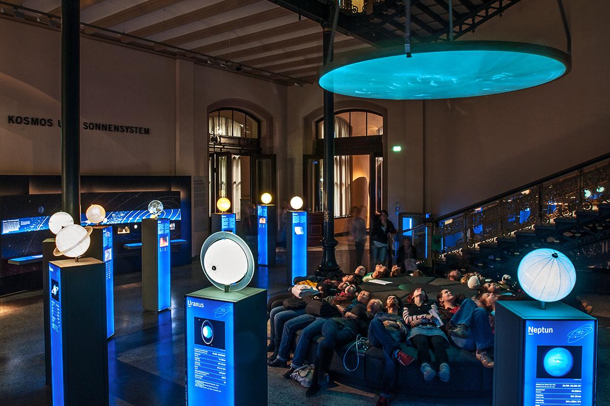 Besucher haben auf der Liege-Insel Platz genommen und betrachten die multimediale Show zur Entstehung des Universums und der Erde. Besucher haben auf der Liege-Insel Platz genommen und betrachten die multimediale Show zur Entstehung des Universums und der Erde.