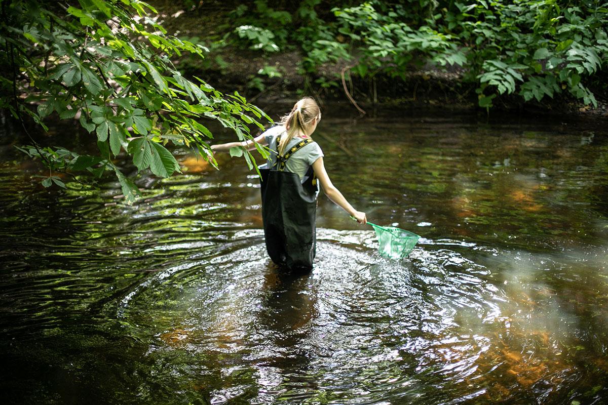 Eine Person steht mit Schutzkleidung im Wasser