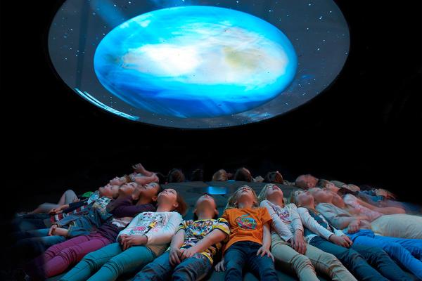 Besucher schauen liegend in Projektionshimmel im Museum für Naturkunde Berlin