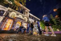 Eine Warteschlange von Menschen am Museum für Naturkunde in der Nacht.