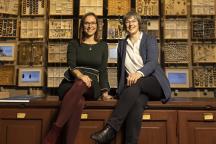 Jana Hoffmann und Christiane Quaiser sitzen vor einer Wand auf Insektenkästen in der Sonderausstellung "digitize!"