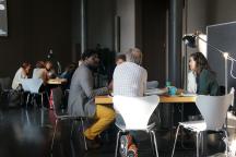 Several people exchange ideas while sitting at tables during a workshop