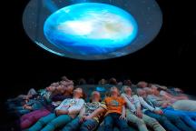 Besucher schauen liegend in Projektionshimmel im Museum für Naturkunde Berlin