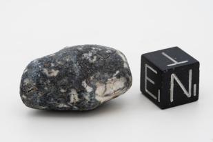Meteorite called Ribeck in relation to a cube on a white background 