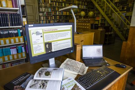 Bücher und Computer an einem Arbeitsplatz in der Bibliothek