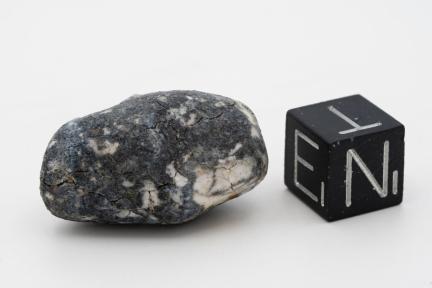 Meteorite called Ribeck in relation to a cube on a white background 